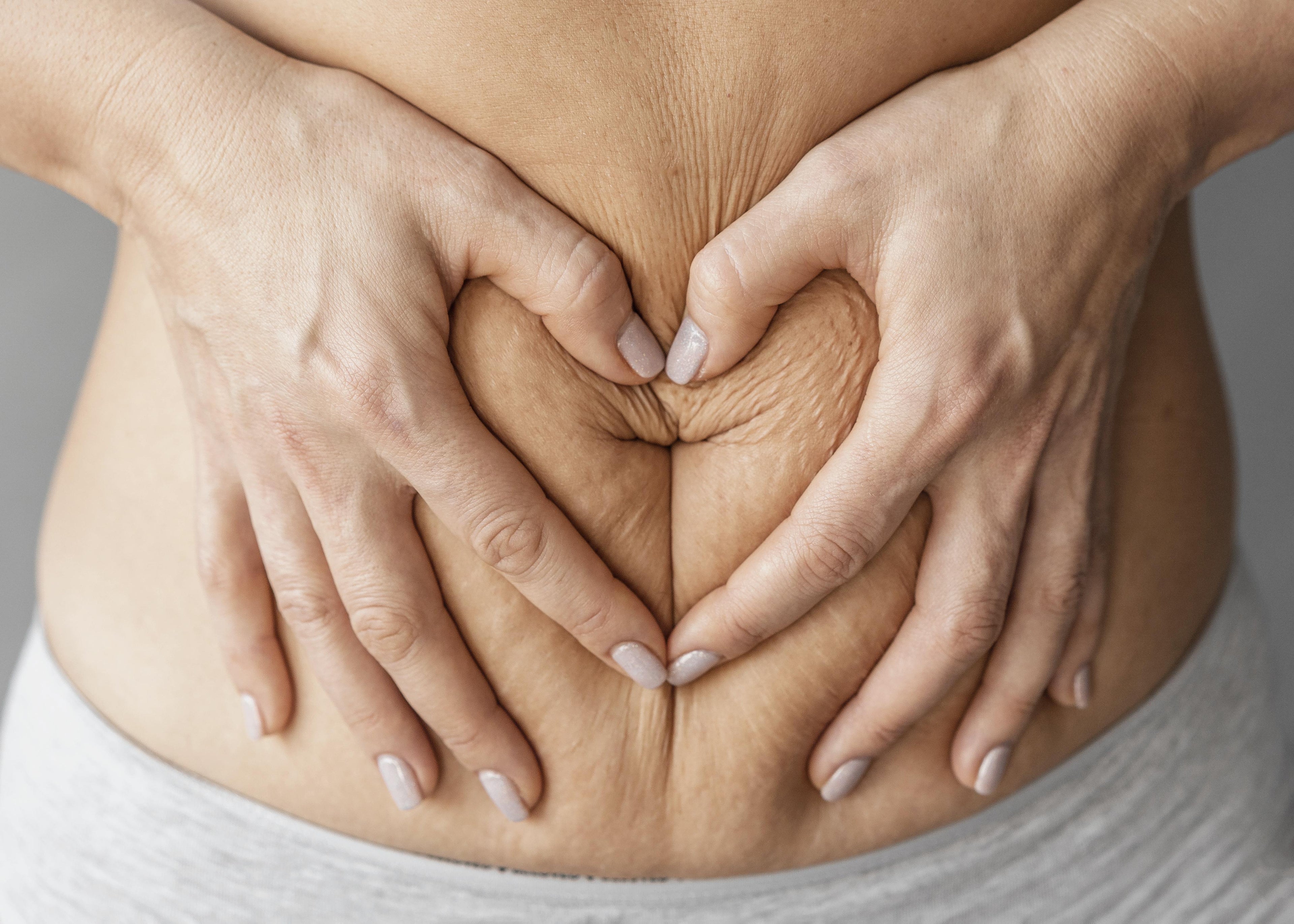 Een postpartum buik met een hartje van handen